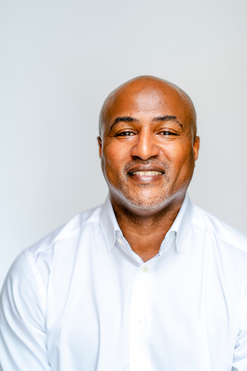 Headshot of Lynde Williams, artist in a white shirt, smiling